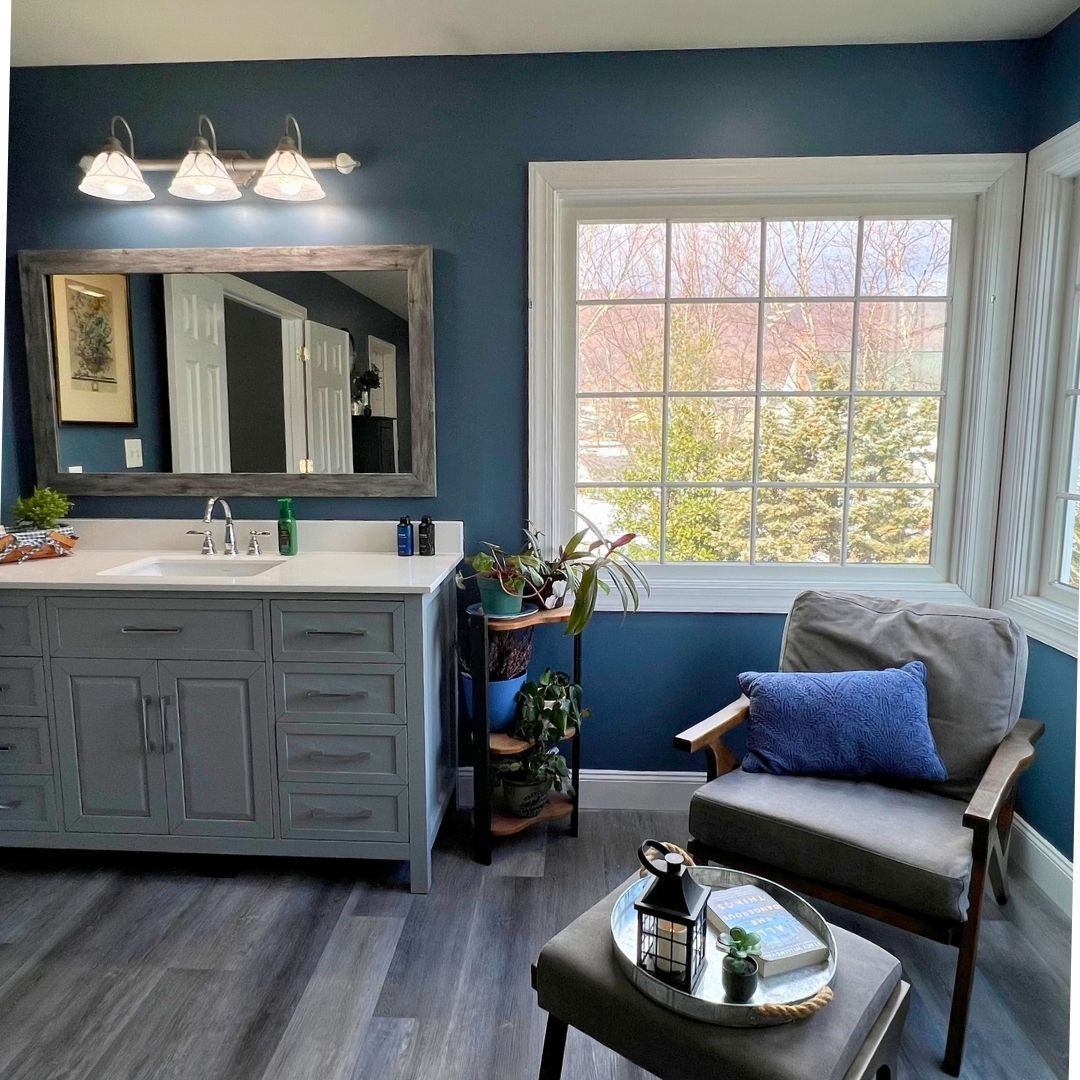 Spacious Bathroom Remodel with Blue Walls, Gray Vanity and Comfy Chair.
