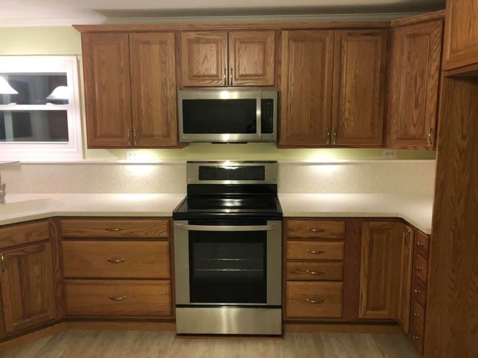 Wooden kitchen with stainless steel stove and microwave, white backsplash, and wood cabinets