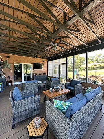 Covered patio with wicker sofas, blue cushions, wood ceiling, and open view of a green yard.