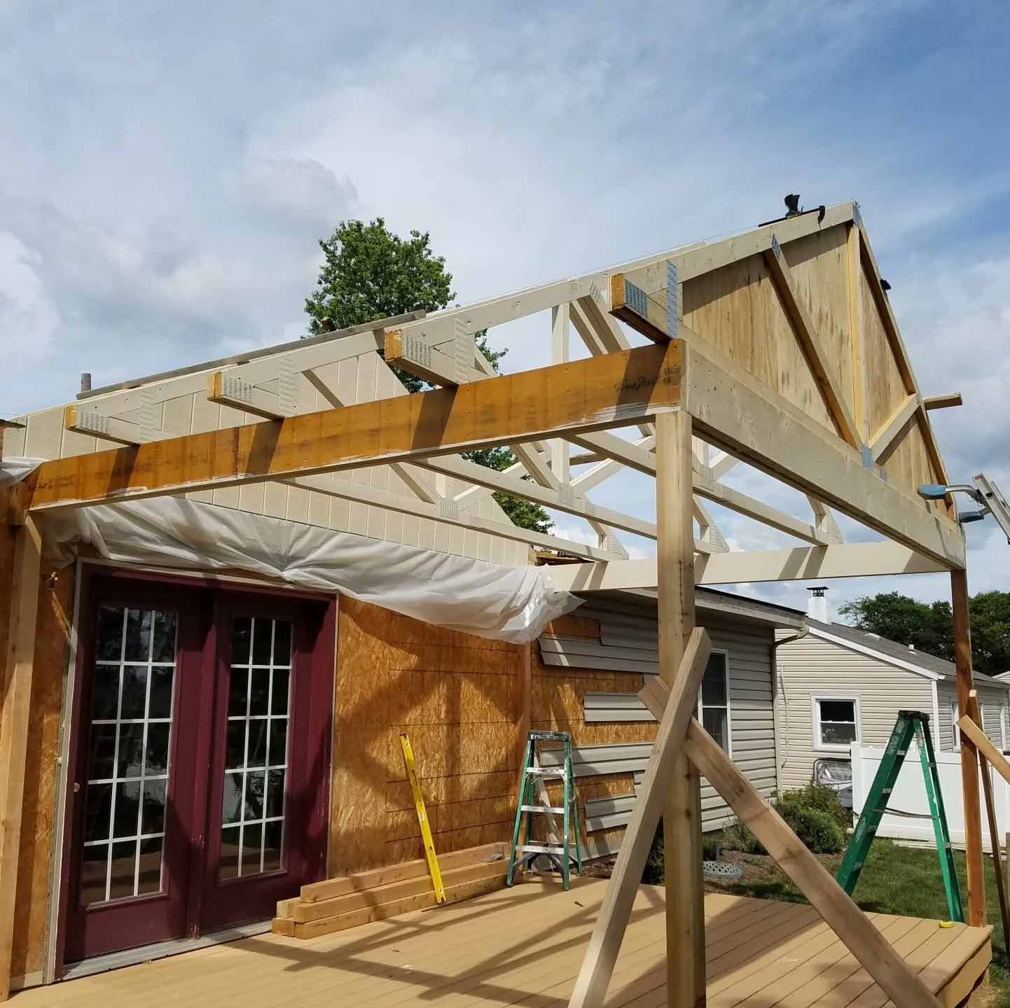 Partially built wooden deck and roof frame over a house under construction