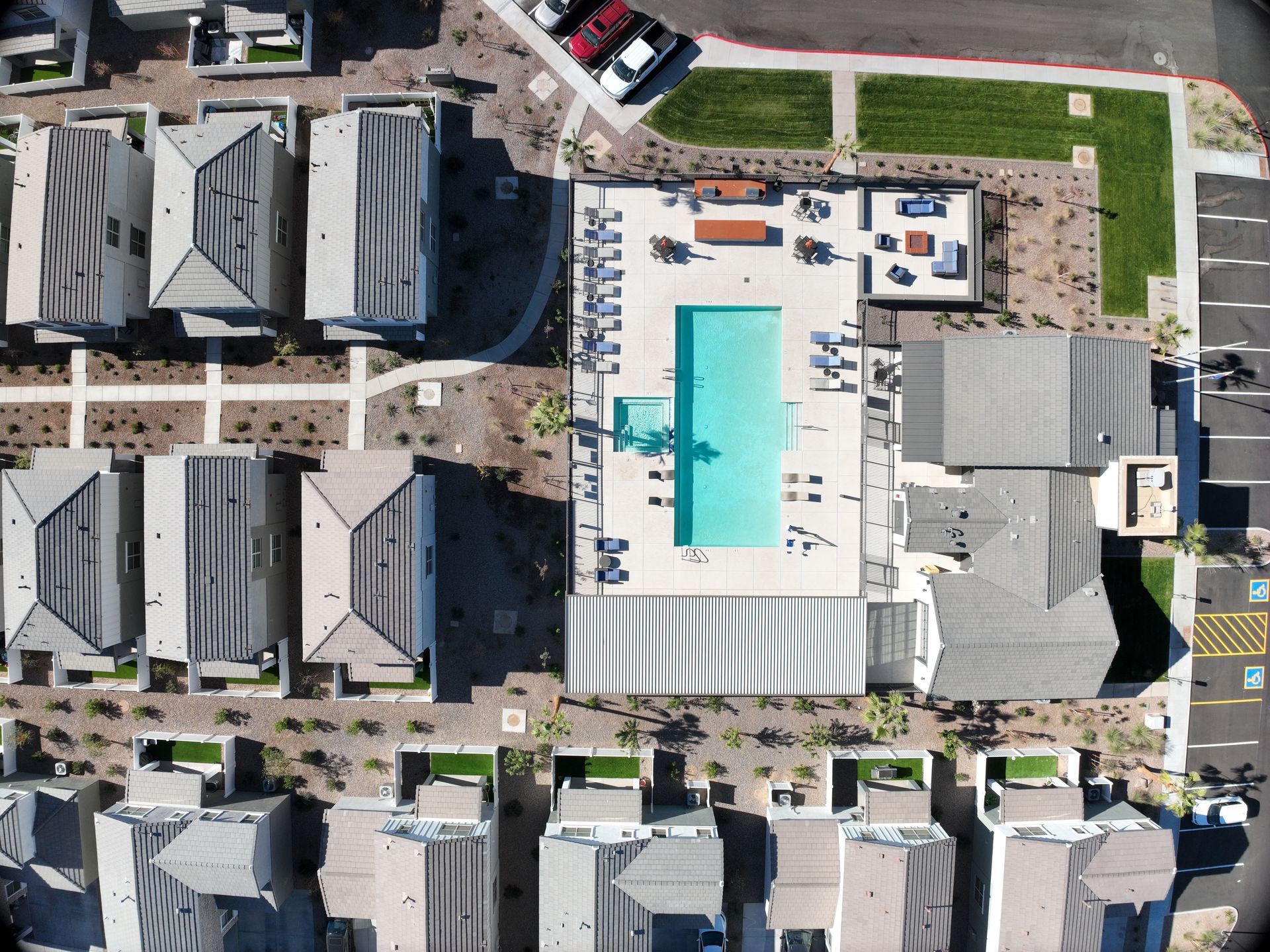 Aerial view of a coastal neighborhood with rows of dark-roofed houses and streets near the shoreline.