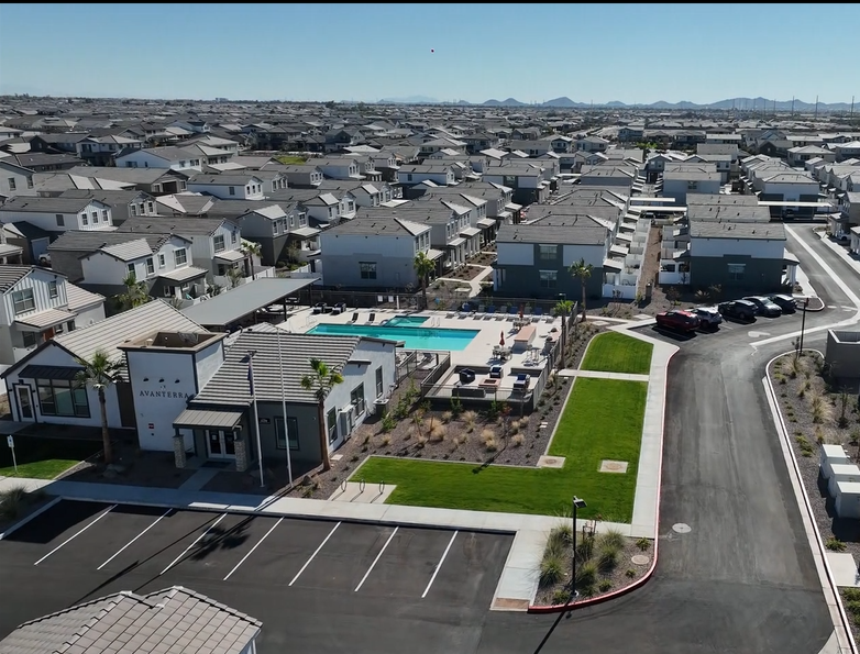 Aerial view of a suburban apartment complex with a swimming pool, parking lot, and landscaped green space
