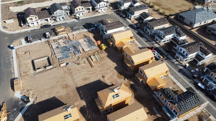 Aerial view of a suburban neighborhood with houses under construction and parked vehicles.