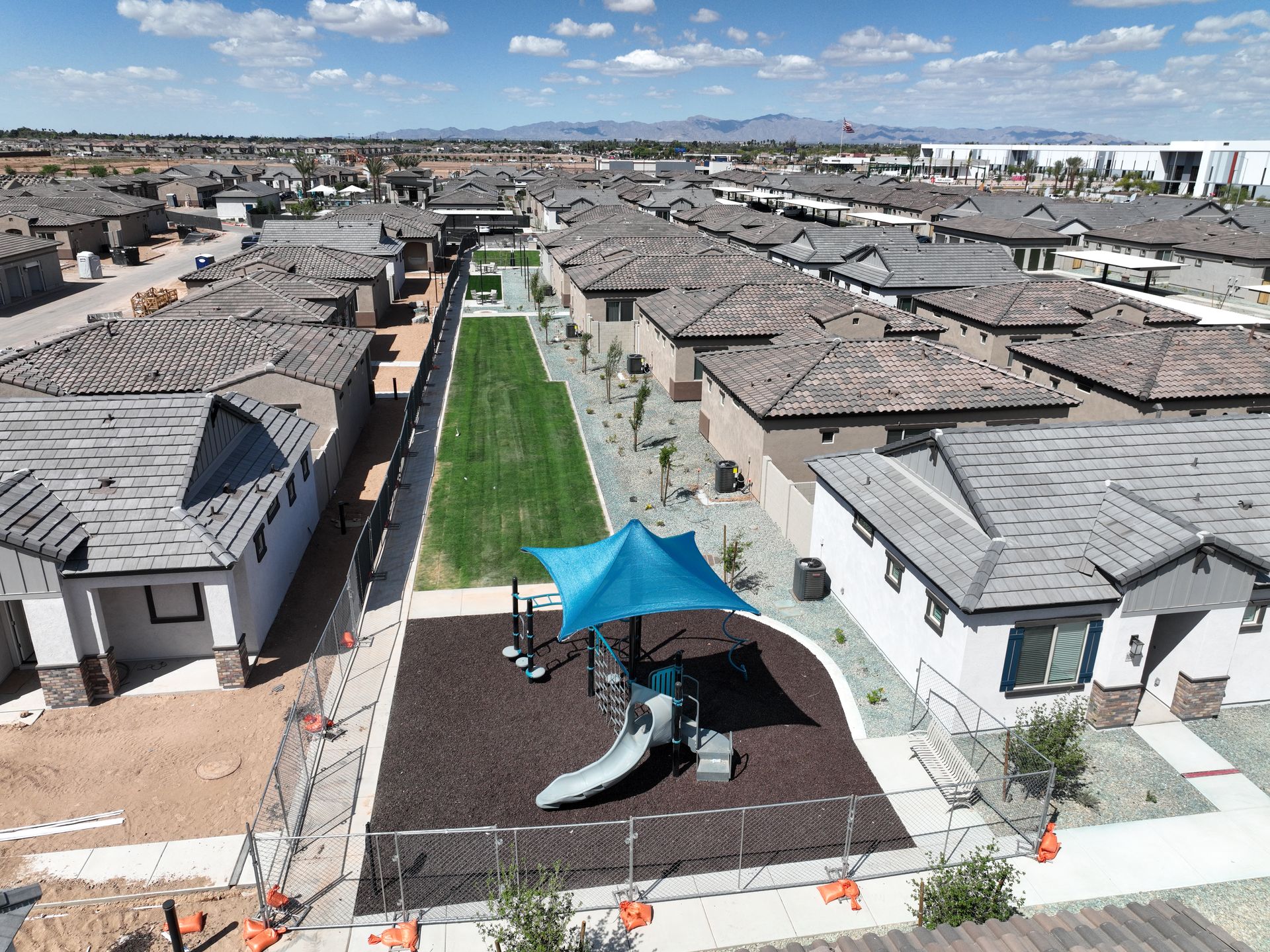 Aerial view of a housing development with rows of gray-roofed homes and a central green walkway