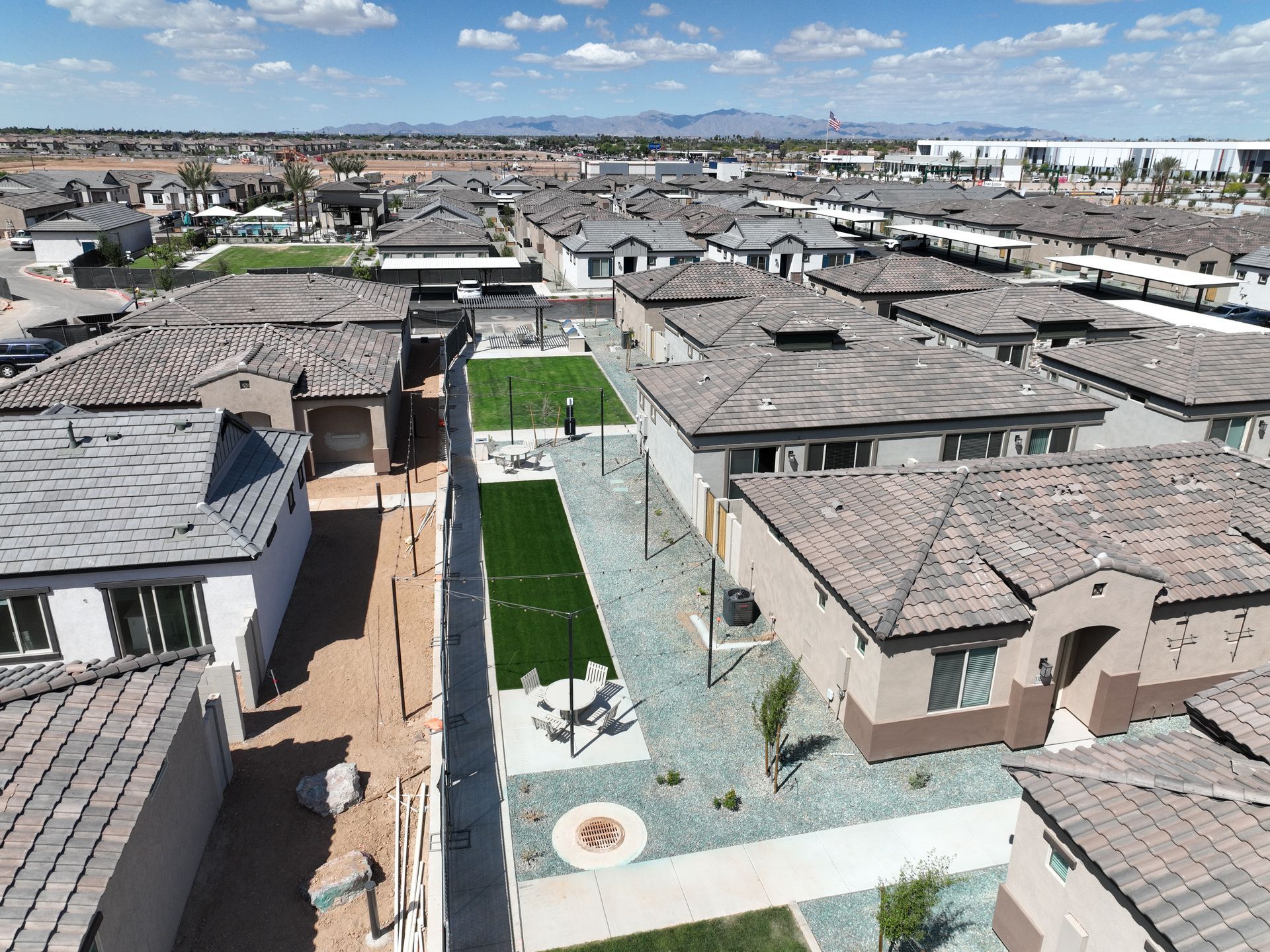 Aerial view of a modern residential neighborhood with a central green courtyard and tiled rooftops.
