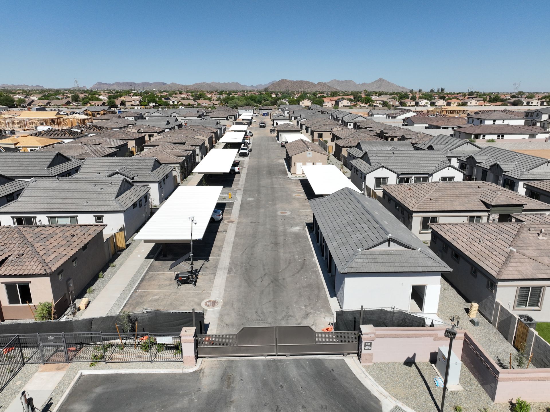 Aerial view of a suburban neighborhood with rows of houses and a wide street under a clear sky