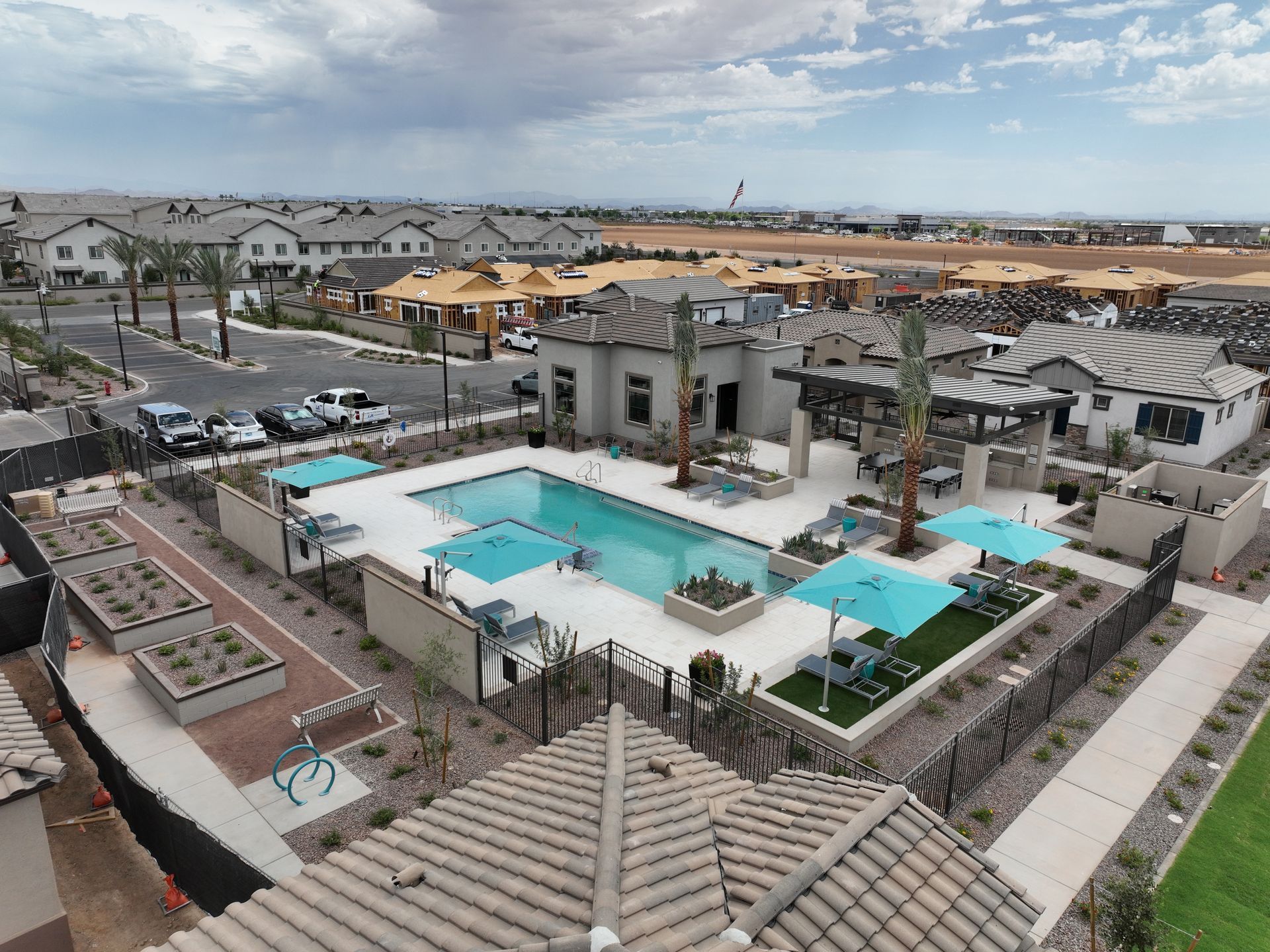 Aerial view of a residential complex with a green lawn, pergola, and swimming pool under a cloudy sky