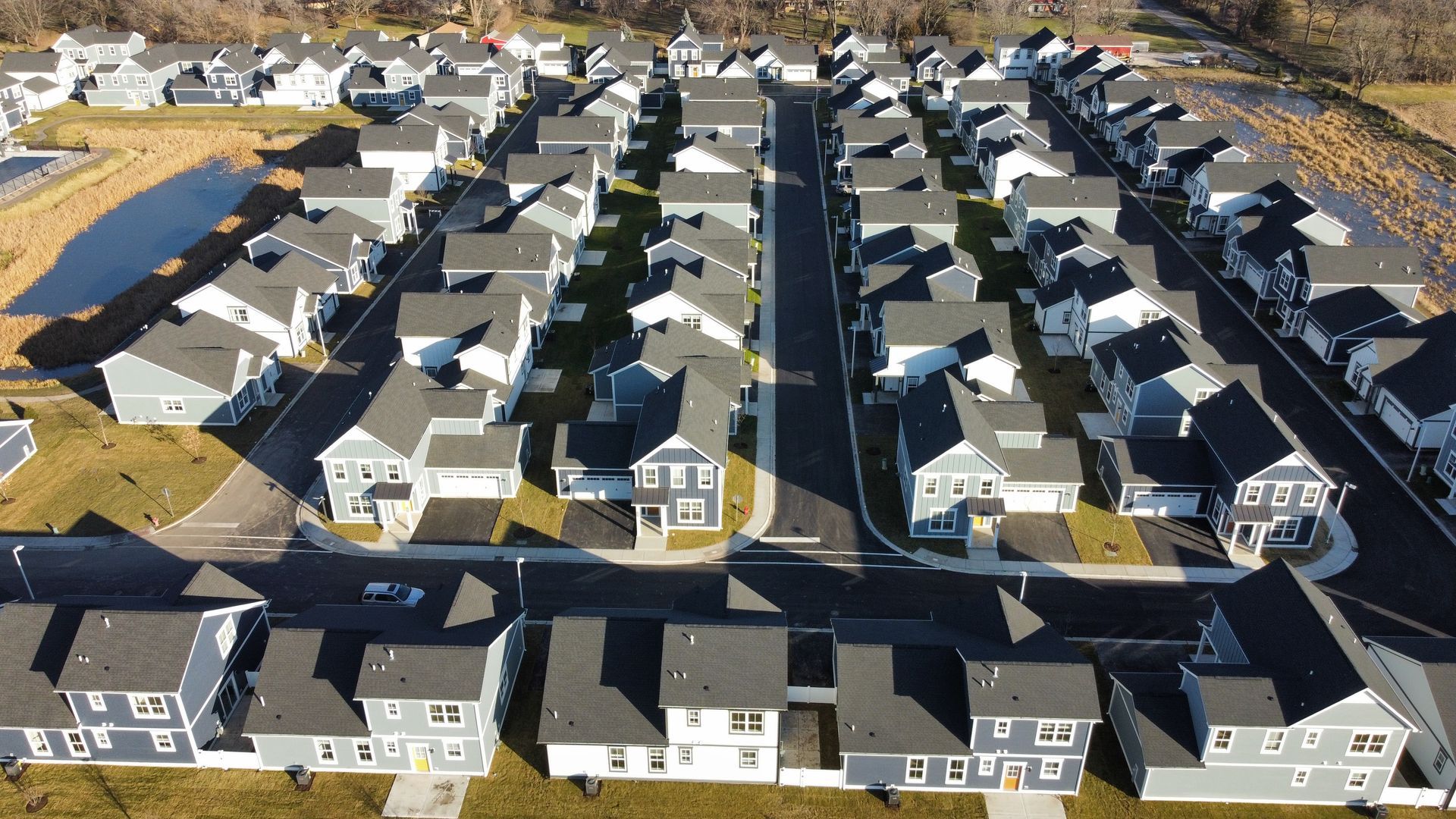 Aerial view of a suburban neighborhood with rows of houses and driveways under construction.