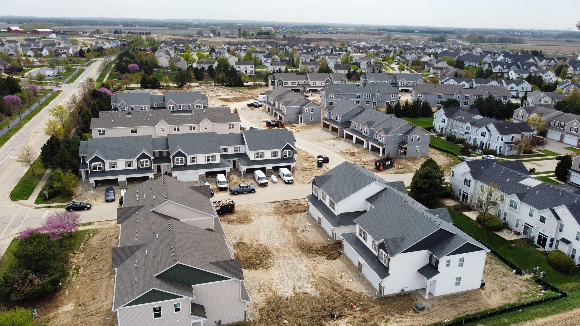 Aerial view of a suburban housing development with rows of gray-roofed houses and streets.