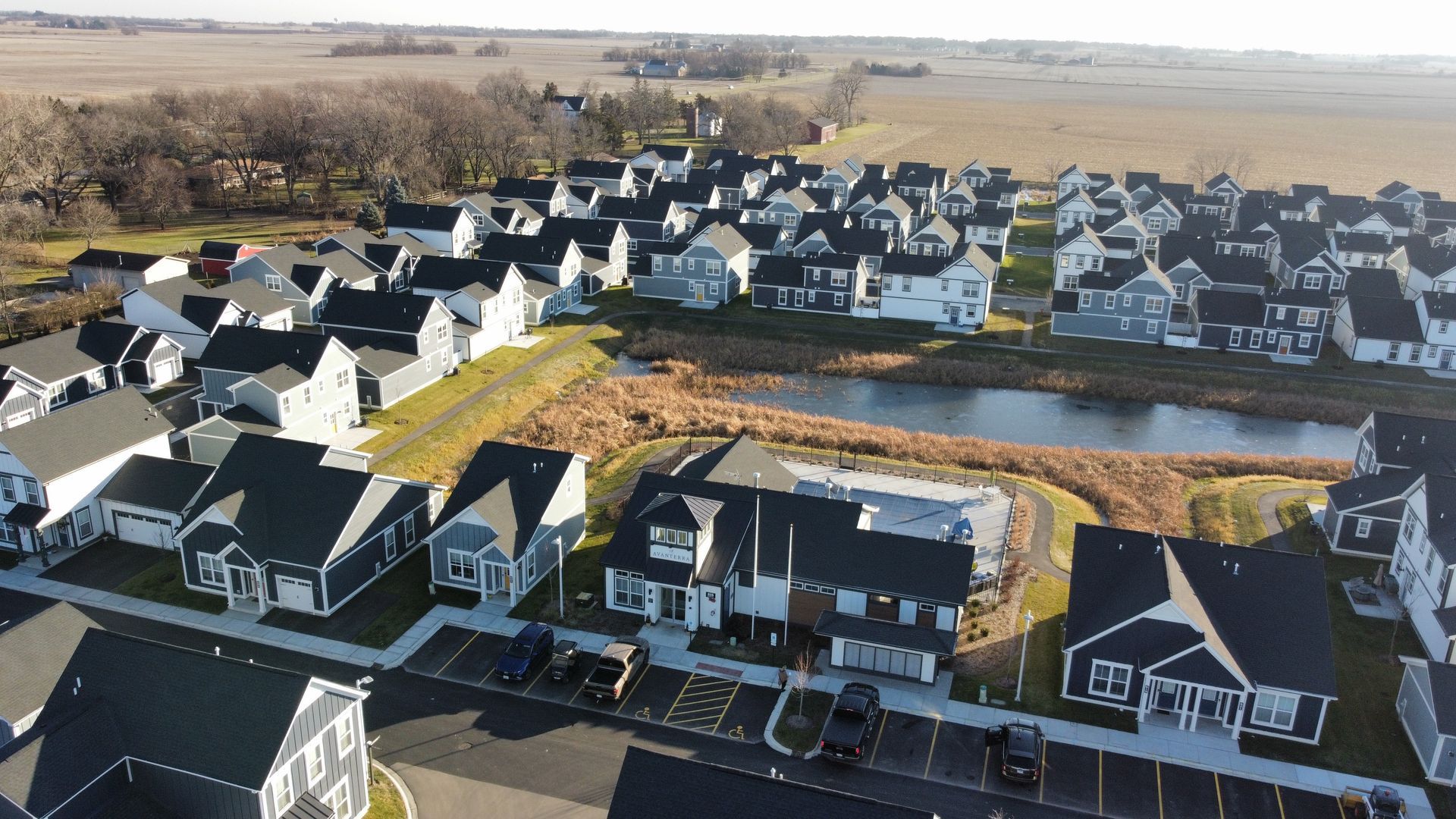 Aerial view of a suburban housing estate with rows of white houses beside open fields.