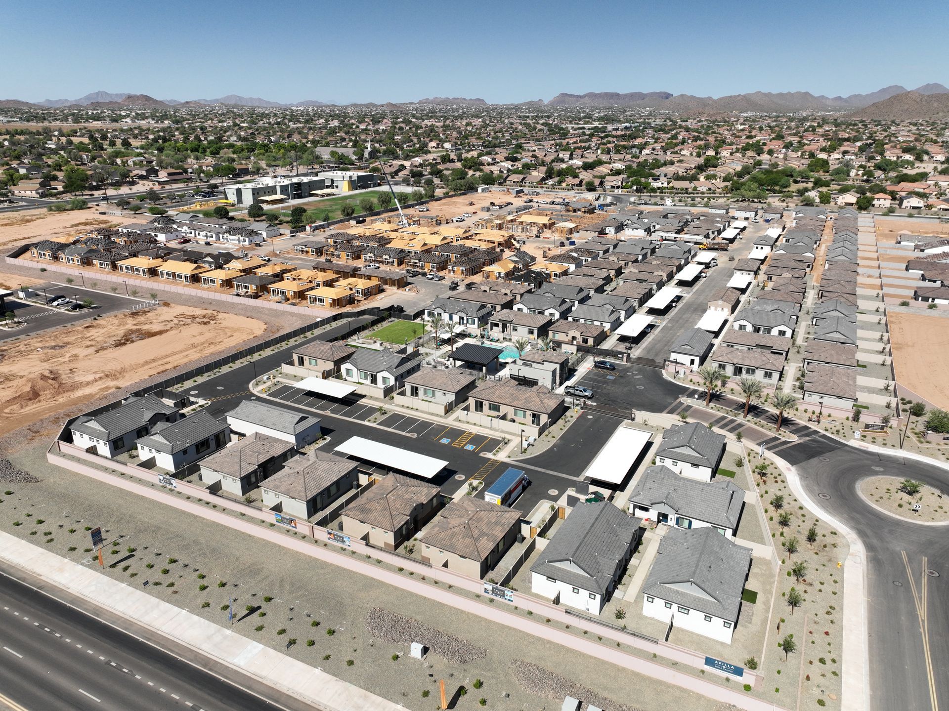 Aerial view of a suburban housing development with streets, houses, and desert landscape