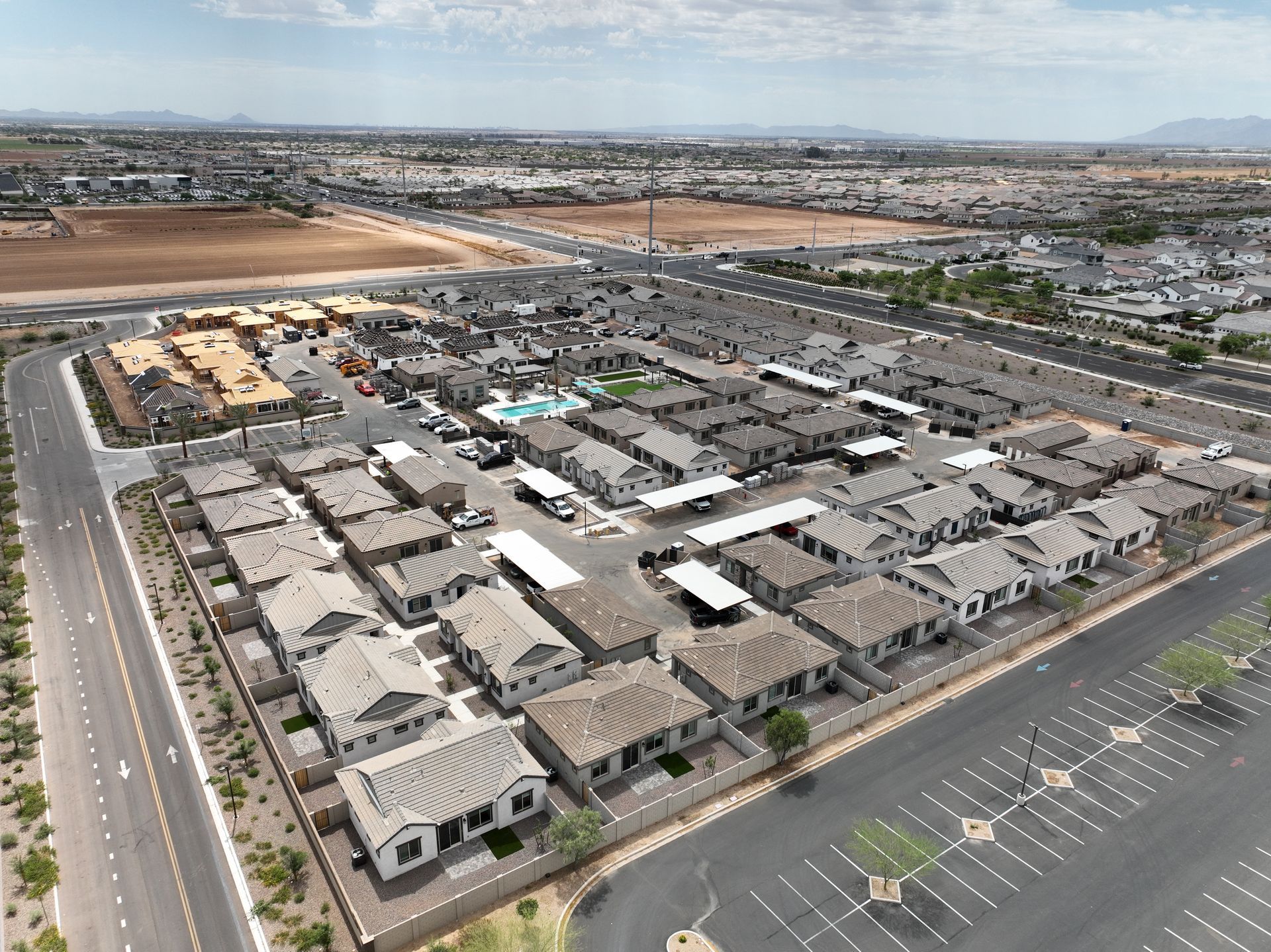 Aerial view of a suburban housing development with rows of beige homes and nearby roads.