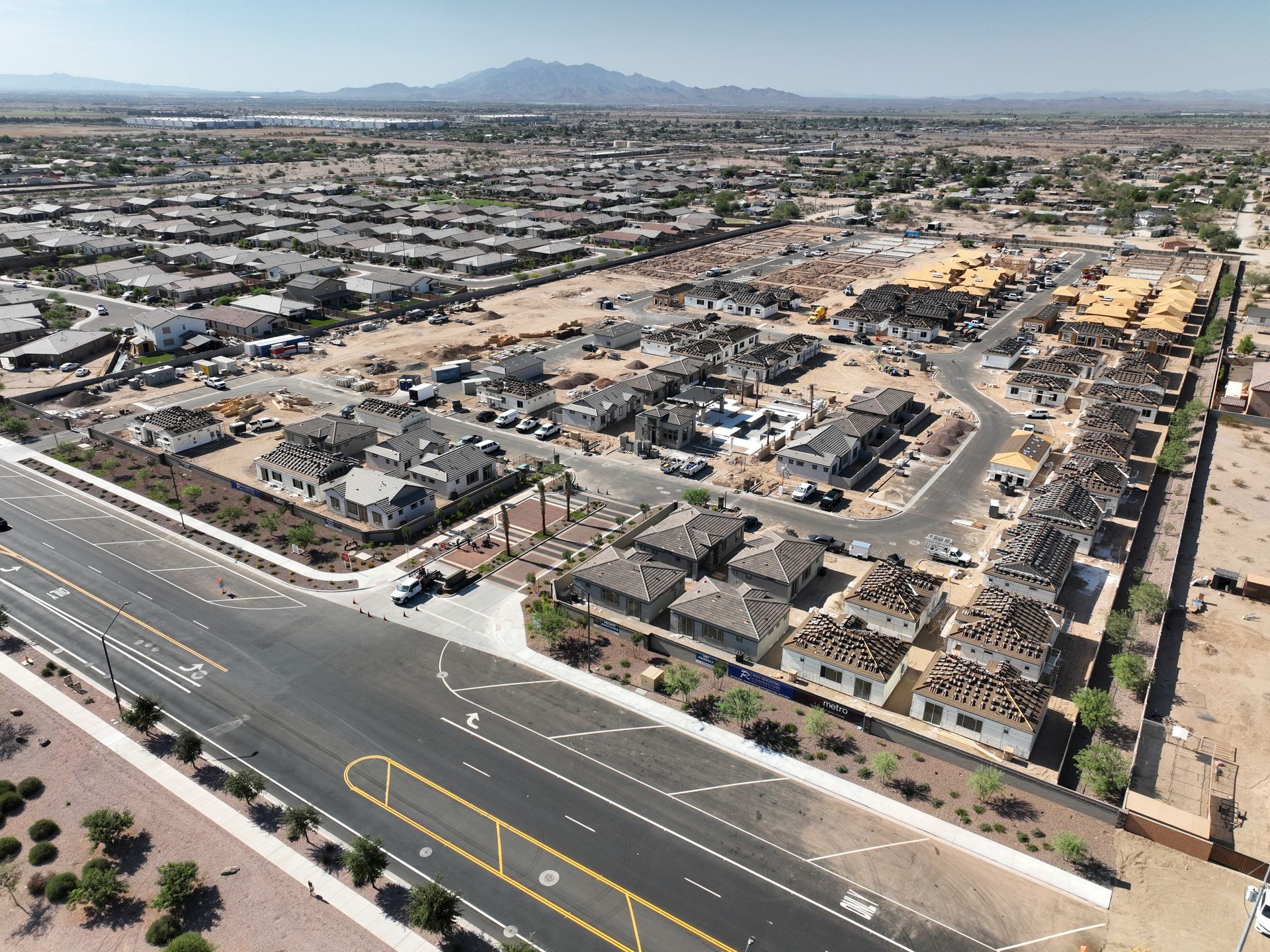 Aerial view of a desert suburb with roads, houses, and mountains in the distance