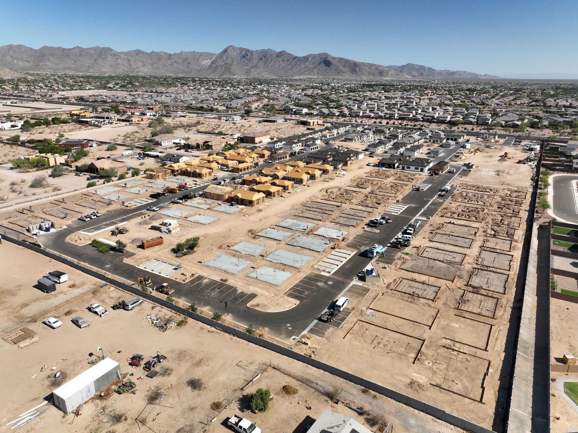 Aerial view of a suburban neighborhood with rows of houses, roads, and desert surroundings.