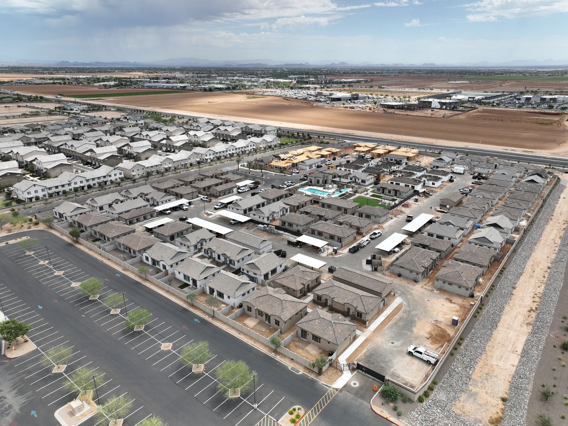 Aerial view of a large apartment home complex with rows of buildings, parking lots, and a central pool