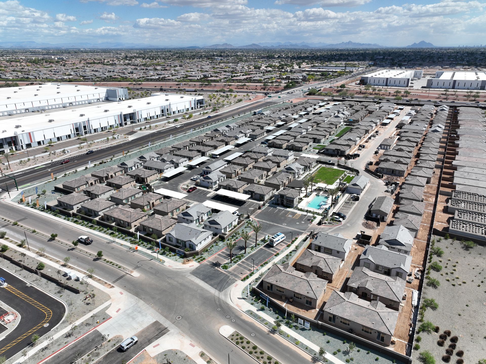 Aerial view of a suburban housing development with a swimming pool, landscaped lawn, and parking lot.