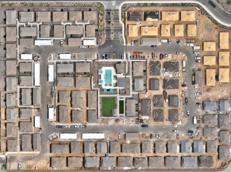 Aerial view of a large suburban housing development with roads and mountains in the distance