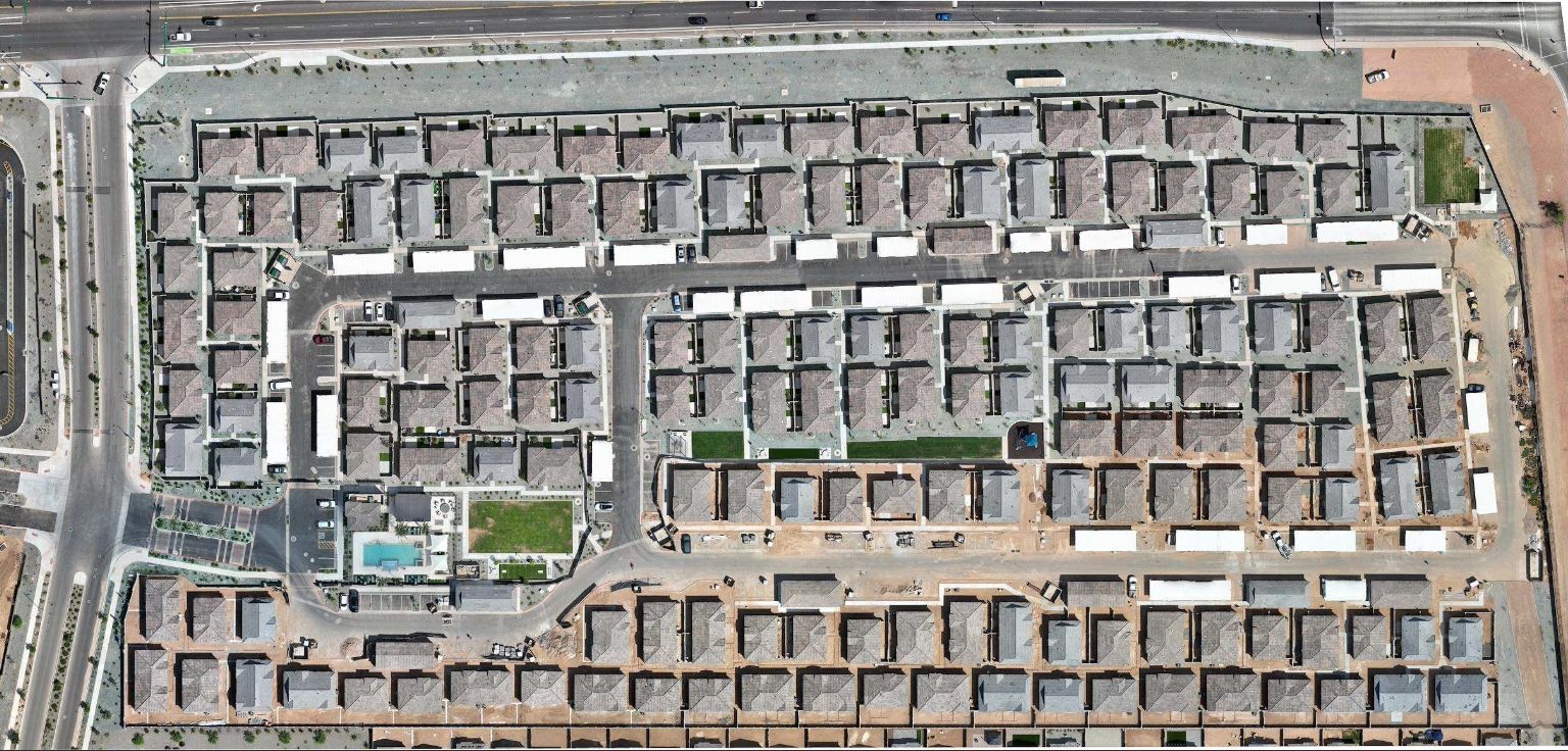 Aerial view of a residential neighborhood with rows of beige houses and a central pool area.