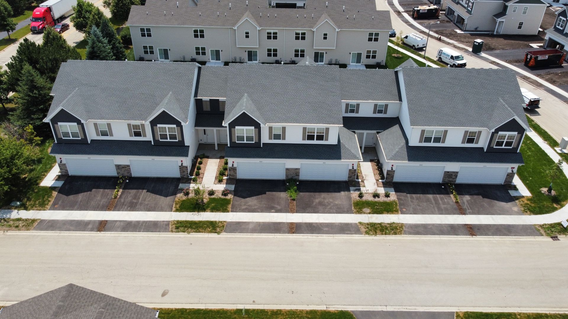 Aerial view of a row of gray townhouses with white trim along a street.