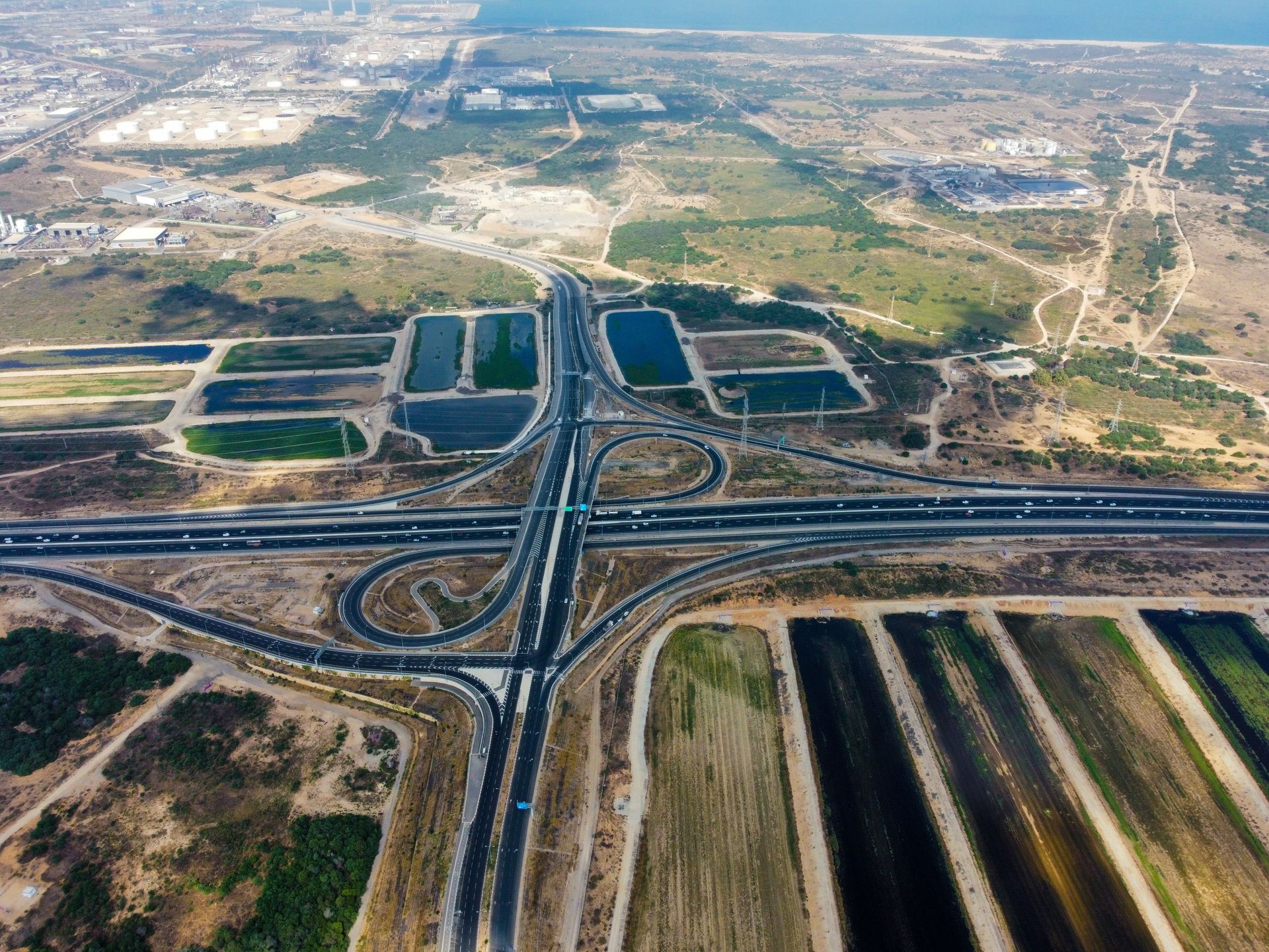 Aerial view of a large highway interchange crossing dry, open landscape with roads and canals.