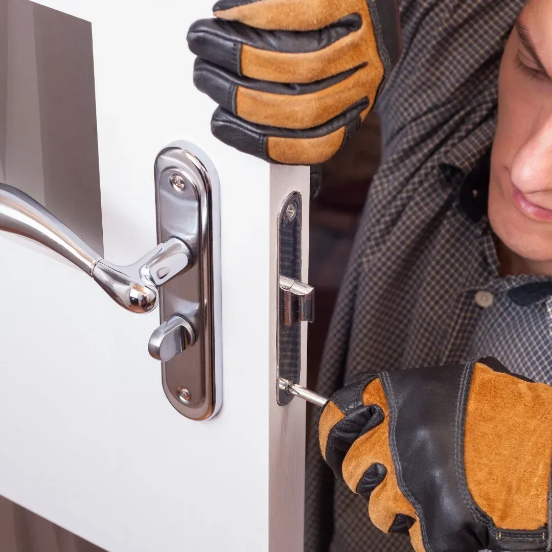 Gloved hands installing a silver door lock on a white door Gloved hands installing a silver door lock on a white door
