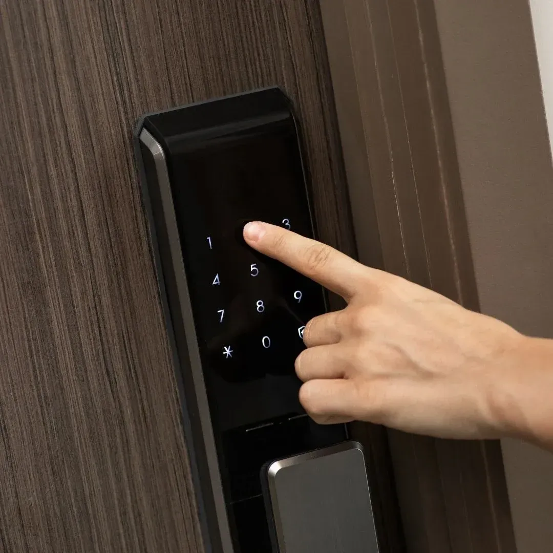 Person entering a PIN on a touchscreen smart lock installed on a home door in Montgomery