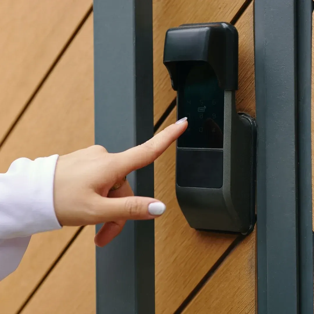 Finger pressing a black wall-mounted keypad on a wooden doorframe Finger pressing a black wall-mounted keypad on a wooden doorframe