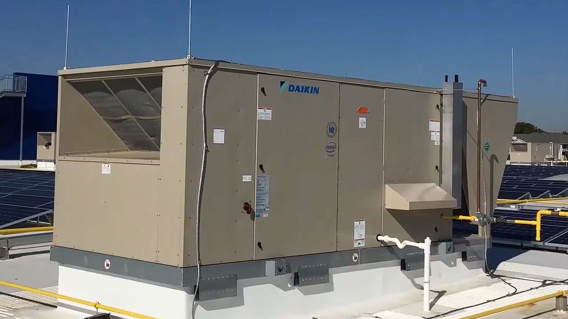Large beige rooftop HVAC unit on a snowy roof under a clear blue sky