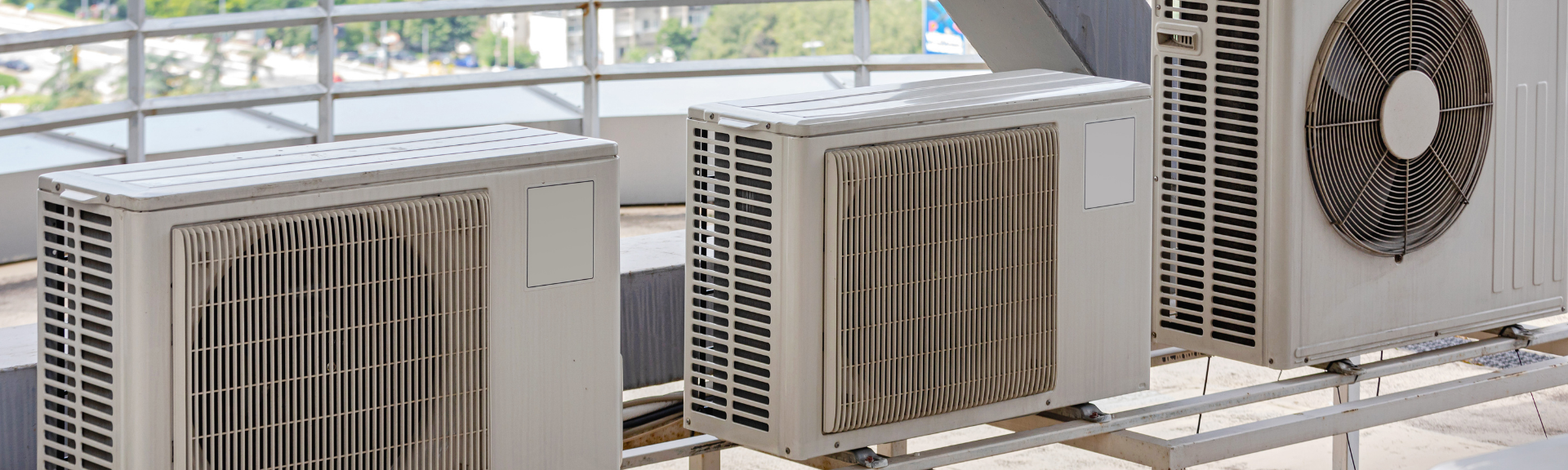 Several outdoor air conditioning units lined up on a balcony or rooftop