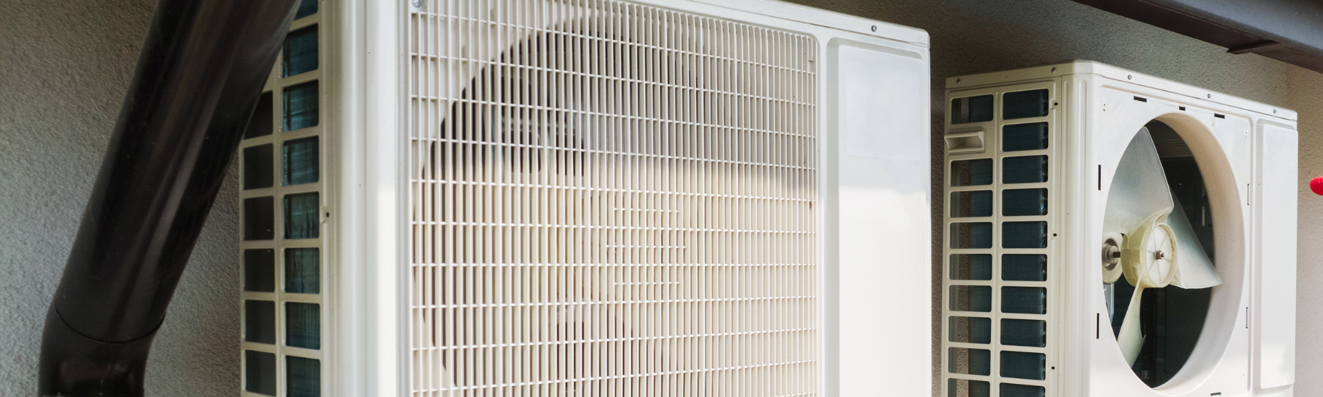 Two white box fans beside a dark curtain, with one fan’s blades visible through a circular grille.