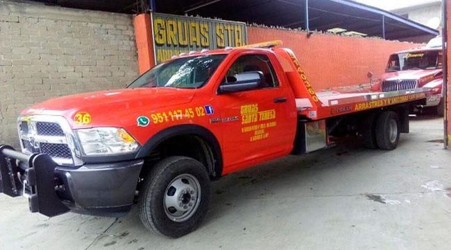 Una grúa roja está estacionada frente a un edificio.