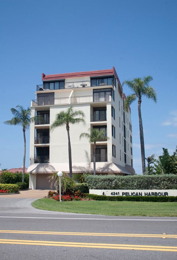 A pelican harbor building with palm trees in front of it