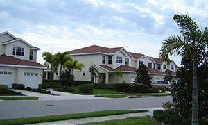 A row of white houses with red roofs in a residential neighborhood.