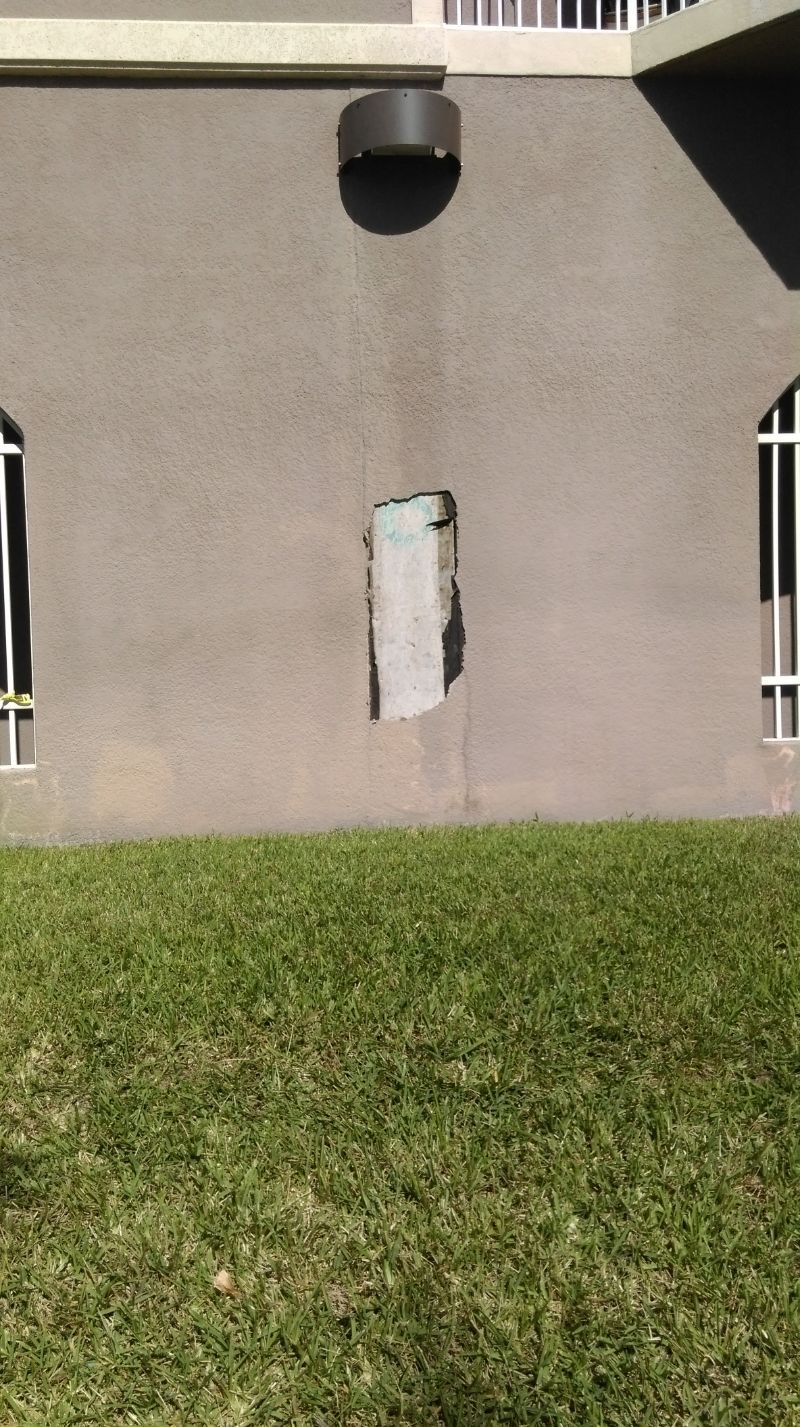 A building with a hole in the wall and two windows.