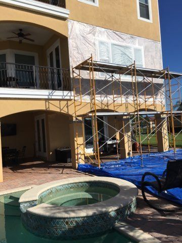 A large house with scaffolding around it and a pool in front of it.