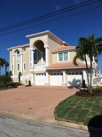 A large house with two garages and a palm tree in front of it.