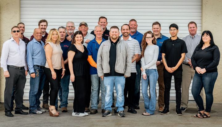 A large group of people are posing for a picture in front of a garage door.