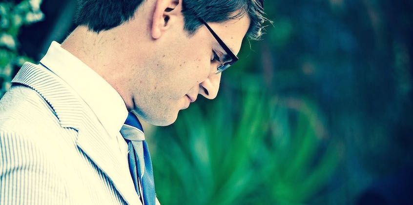 Man in glasses looking down thoughtfully
