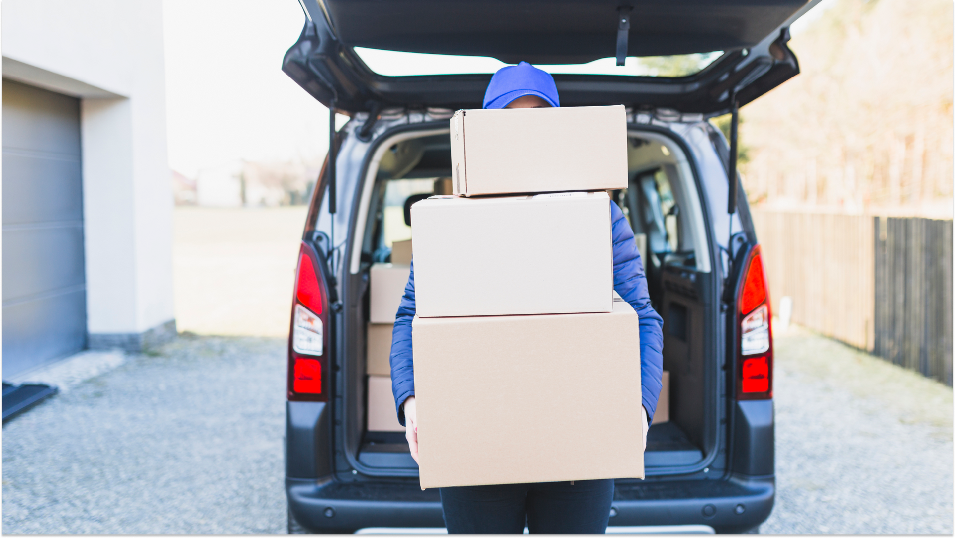 man holding storage boxes by open car trunk