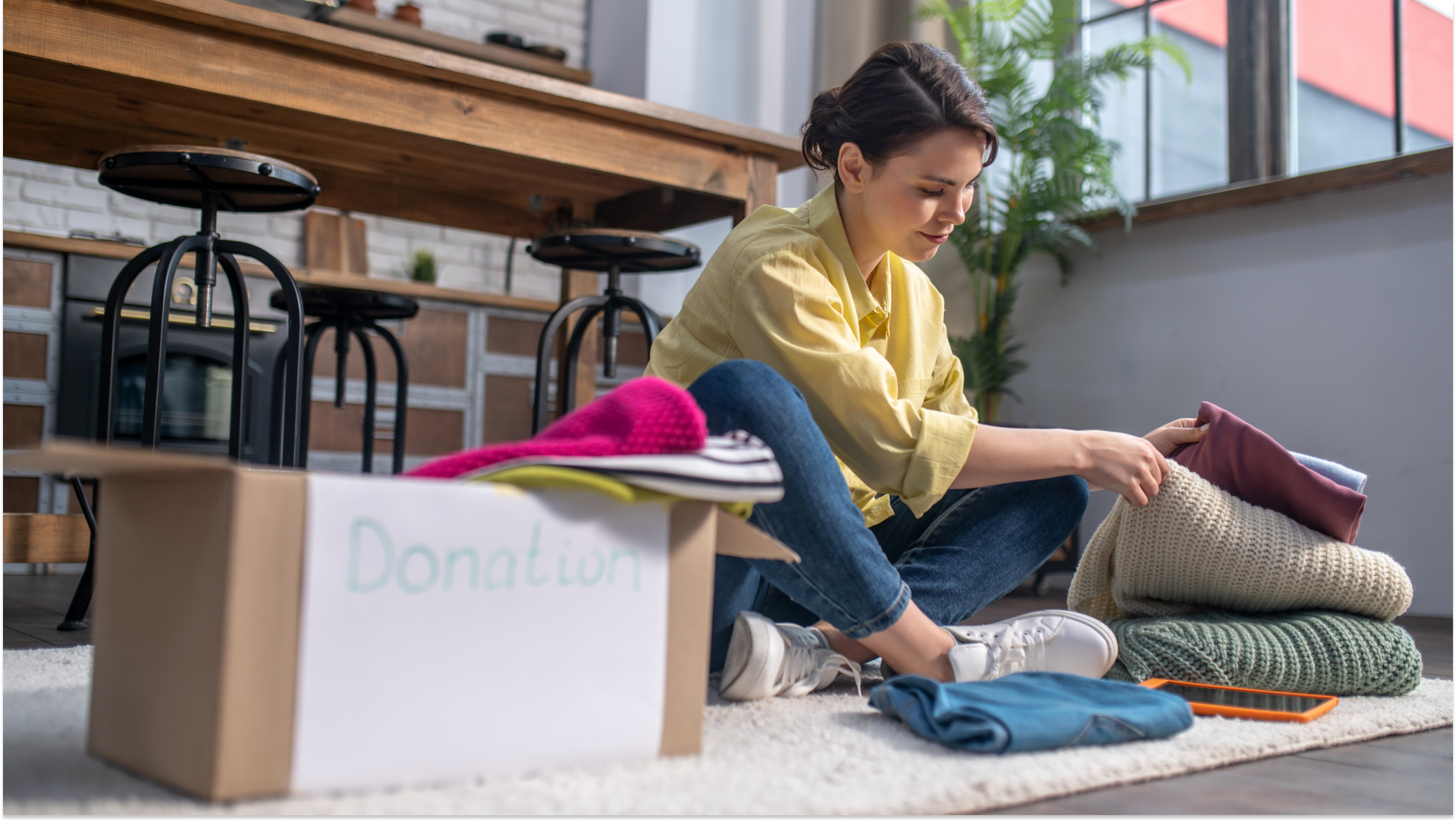woman sitting on floor organizing blankets into a storage box