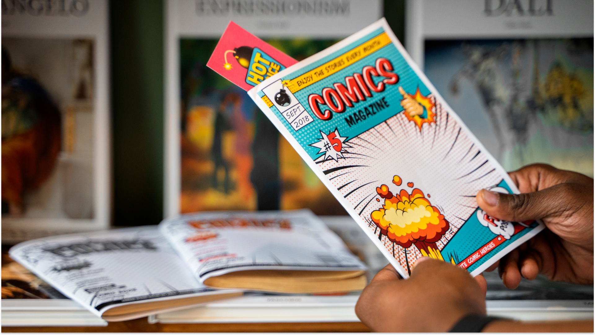 person holding a comic book with brigth wriring with a red bookmark sticking out