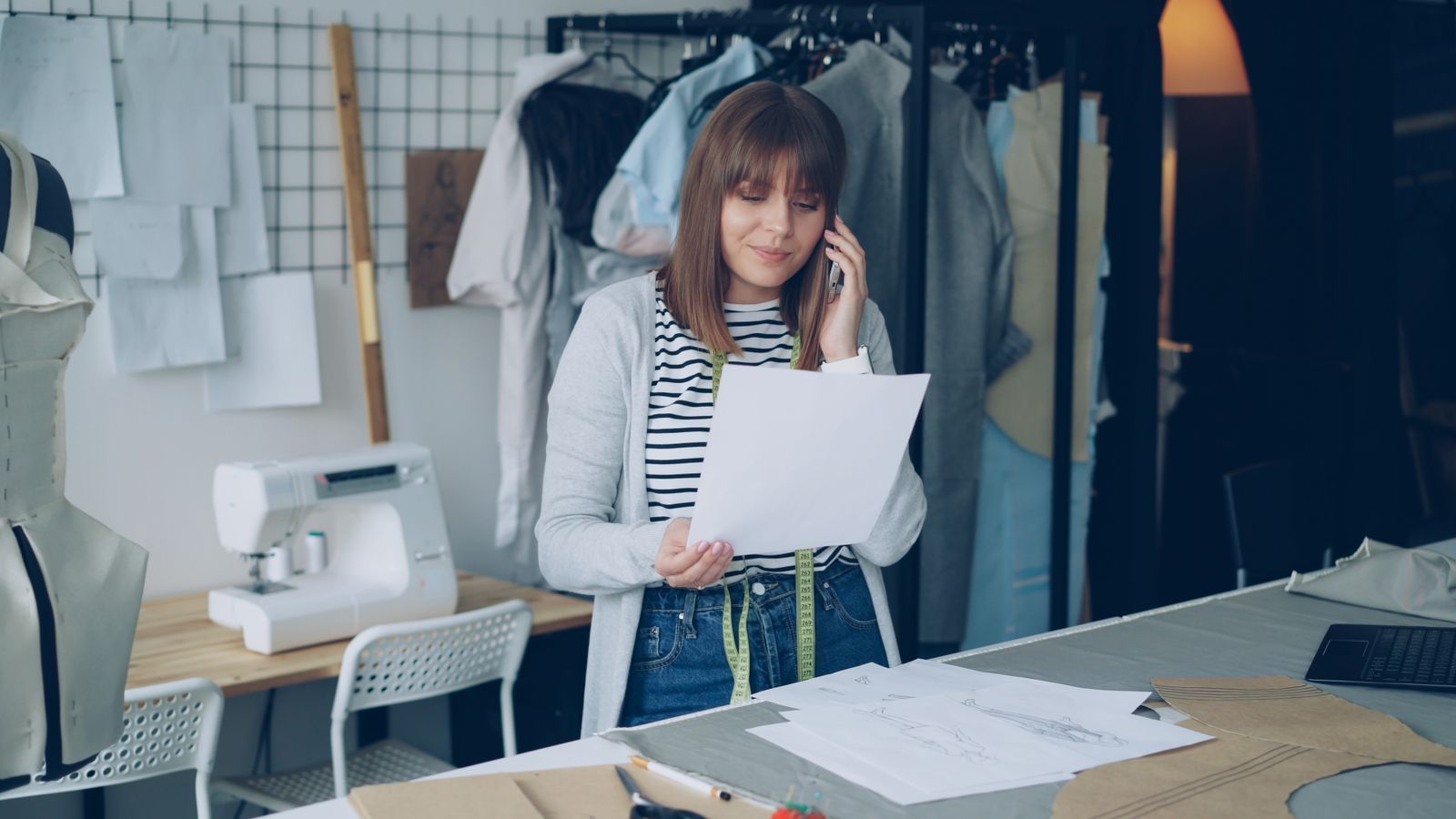 Woman on the phone reviewing paperwork in a small business workspace