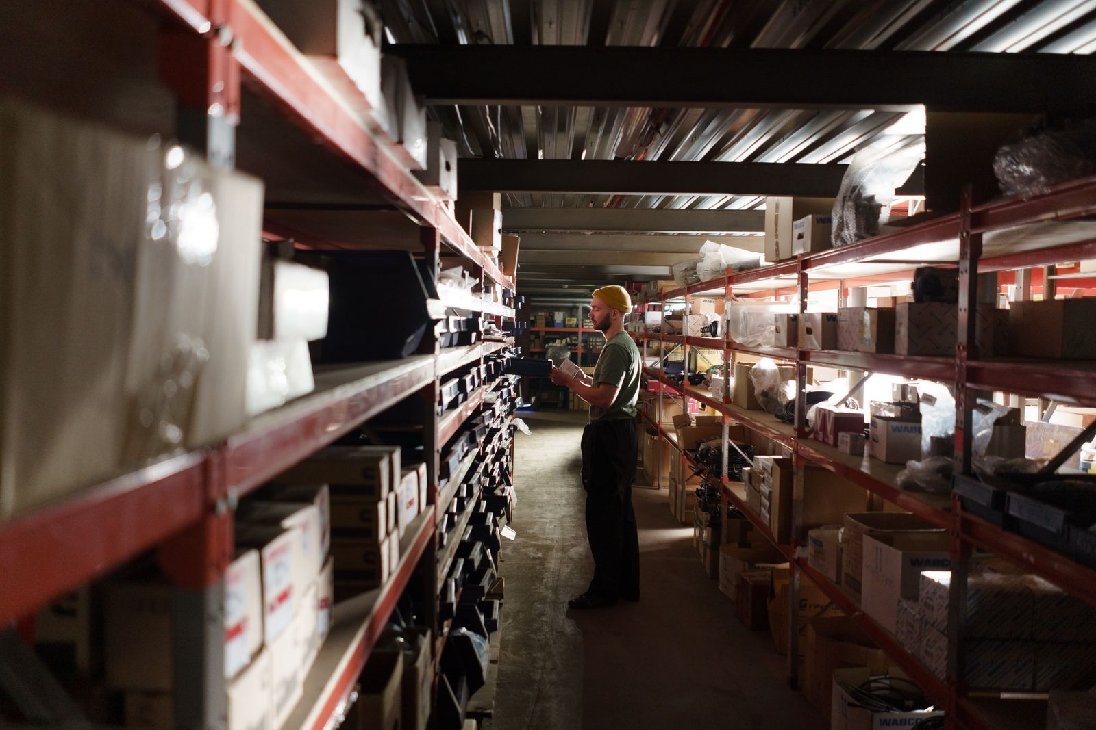 Man checking items on storage shelves in an aisle