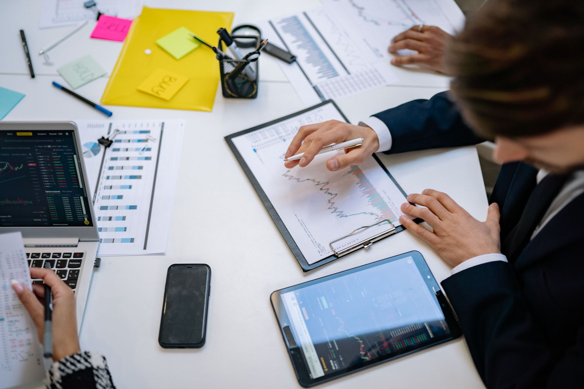 Person sketching UI design concepts in a spiral notebook with a pink pen.