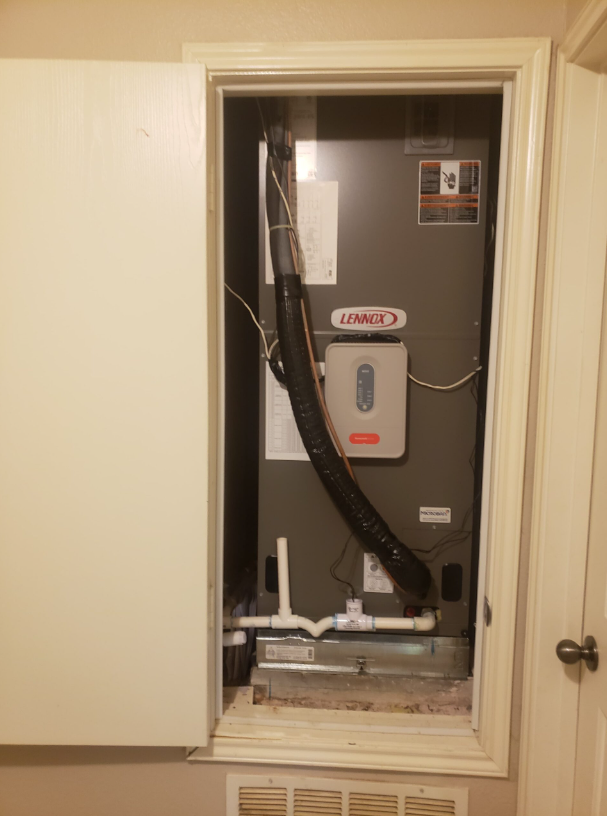 Open HVAC closet with exposed furnace, wires, and access panel in a hallway wall.