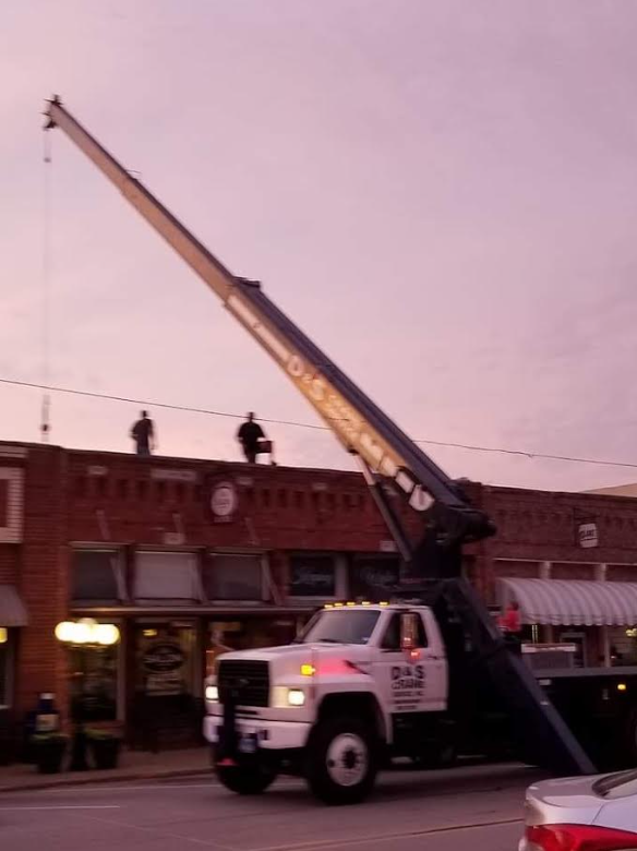 Utility truck with extended crane raised over storefronts at dusk on a city street