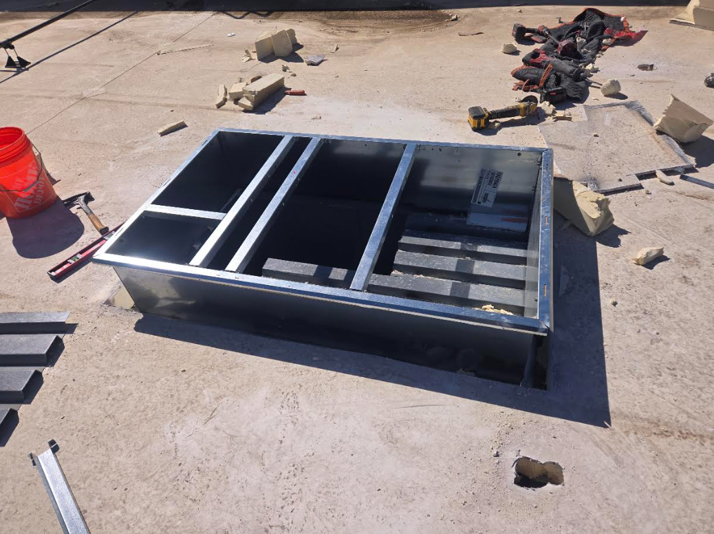 Black metal frame or equipment panel on concrete, with cables and tools in the background