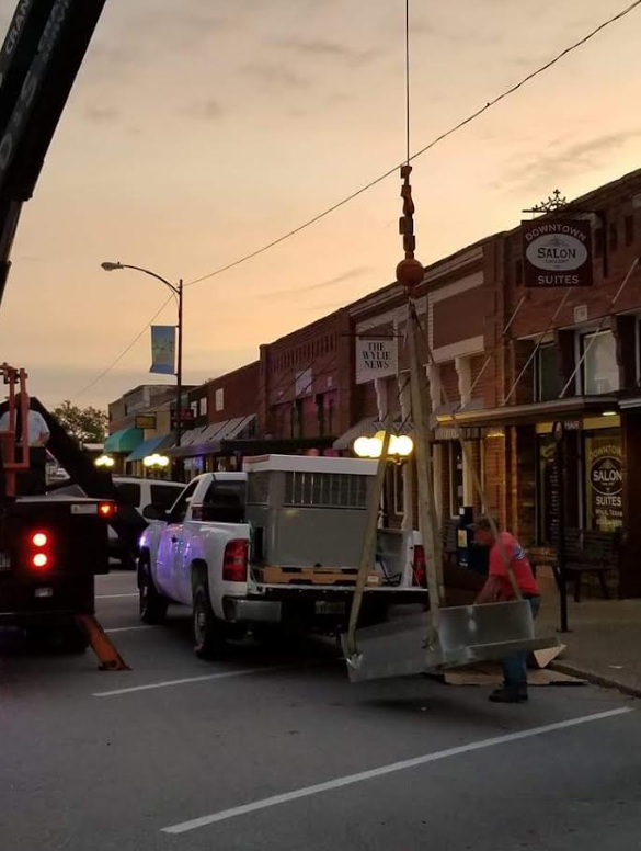 Streetwork crew beside a white utility truck on a small-town street at dusk