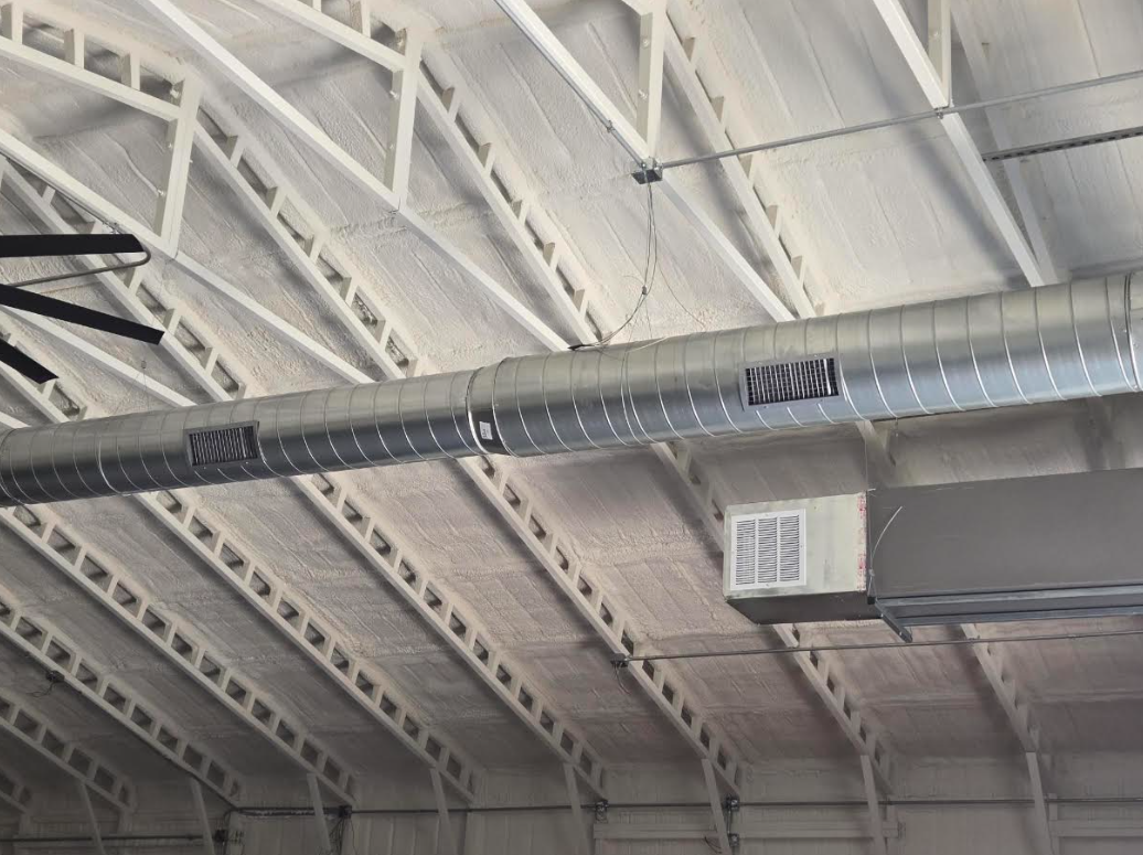 Industrial ceiling with exposed beams and a large silver ventilation duct