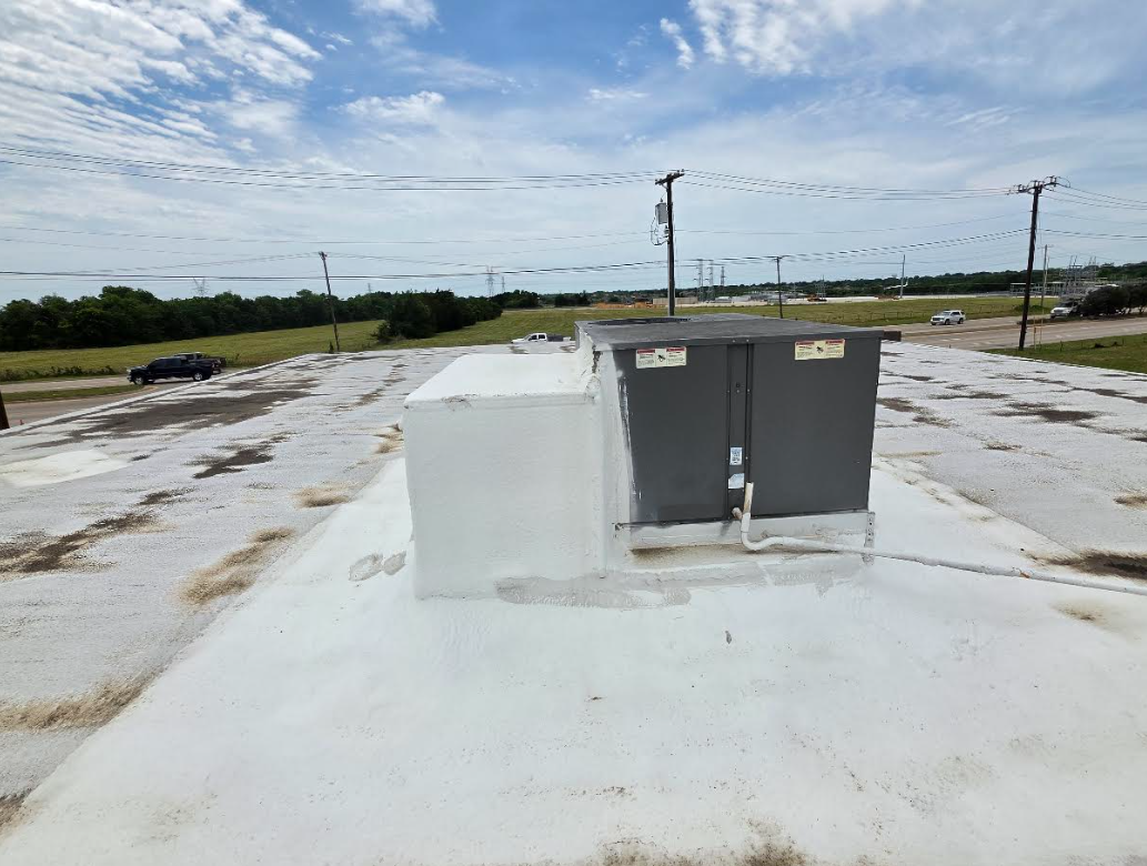 Rooftop HVAC unit on a flat white roof under a cloudy sky